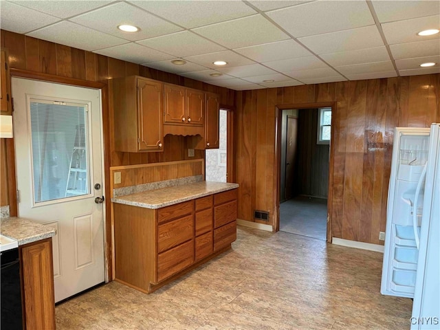 kitchen featuring a drop ceiling and wood walls