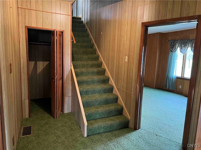 stairway featuring carpet and wood walls