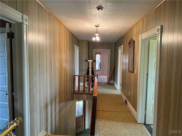 hallway featuring light carpet and wooden walls