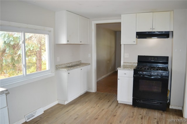 kitchen with light stone counters, white cabinetry, light hardwood / wood-style flooring, and gas stove