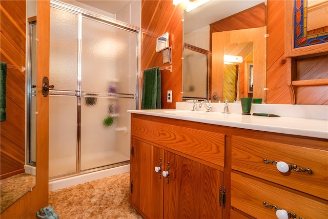 bathroom with vanity, wooden walls, and a shower with door