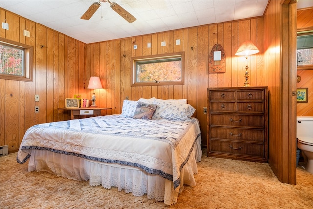 bedroom featuring light carpet, wooden walls, and ceiling fan