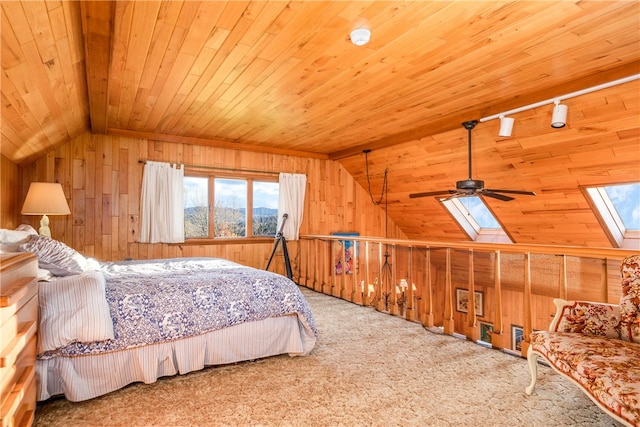 carpeted bedroom featuring vaulted ceiling with skylight, wood ceiling, wood walls, and ceiling fan