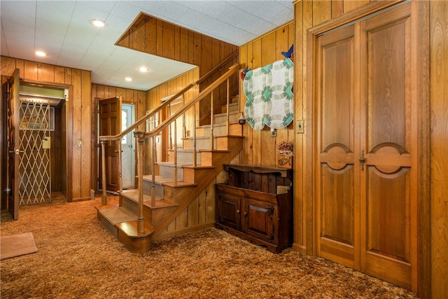 staircase featuring carpet and wooden walls
