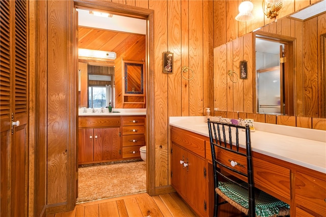 bathroom with hardwood / wood-style floors, vanity, wooden walls, and toilet