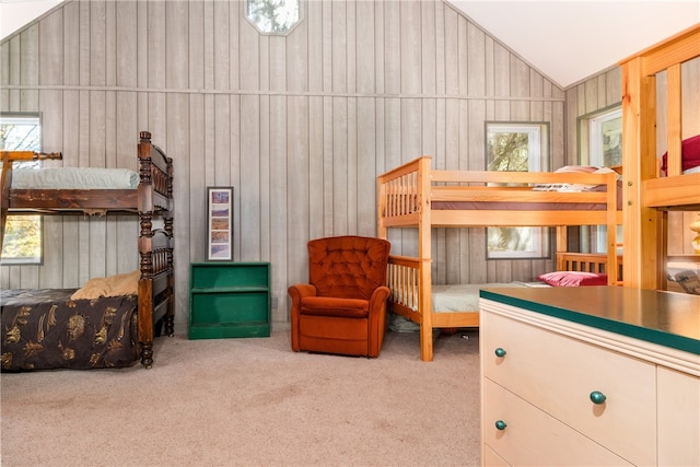 carpeted bedroom with wood walls and vaulted ceiling