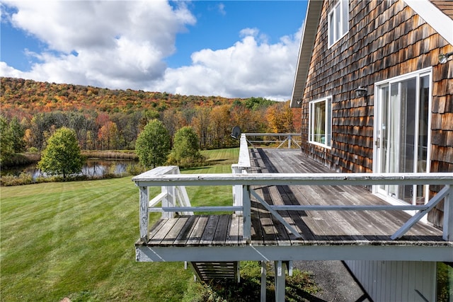 wooden terrace featuring a water view and a lawn