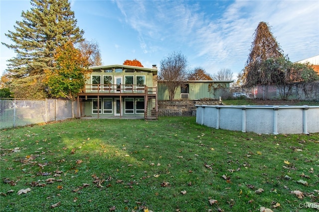 rear view of house featuring a lawn and a fenced in pool