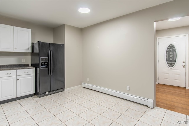 kitchen featuring light wood-type flooring, baseboard heating, black fridge, and white cabinets