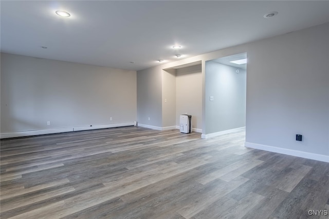 empty room with wood-type flooring and a baseboard radiator