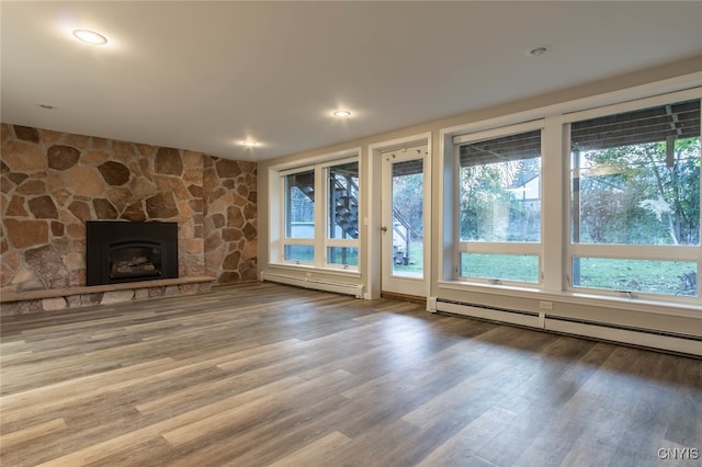 unfurnished living room with hardwood / wood-style flooring, a baseboard radiator, and a fireplace