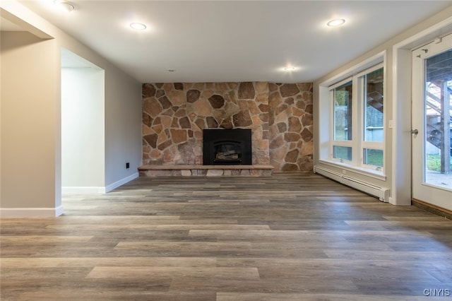 unfurnished living room with a wealth of natural light, a baseboard heating unit, and hardwood / wood-style flooring