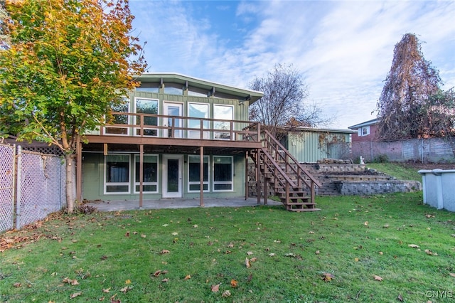 back of house with a wooden deck, a patio, and a yard