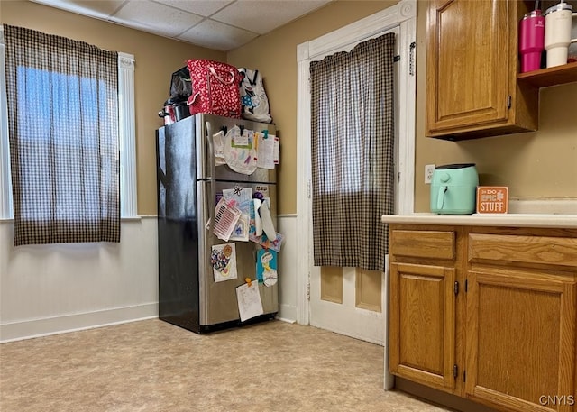 kitchen featuring stainless steel refrigerator, a drop ceiling, and light colored carpet