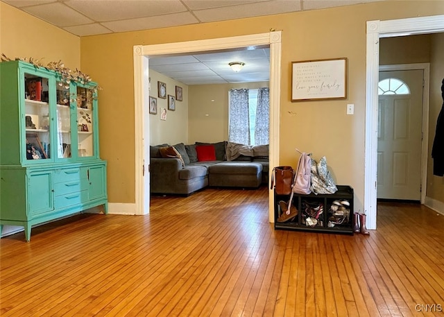 living room featuring wood-type flooring and a drop ceiling