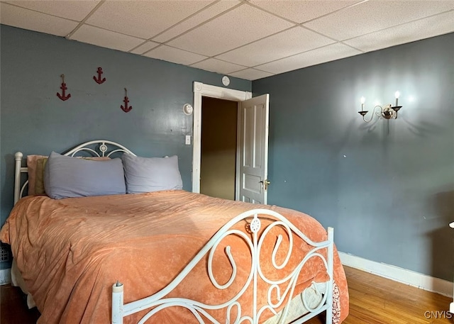 bedroom with a paneled ceiling and hardwood / wood-style floors