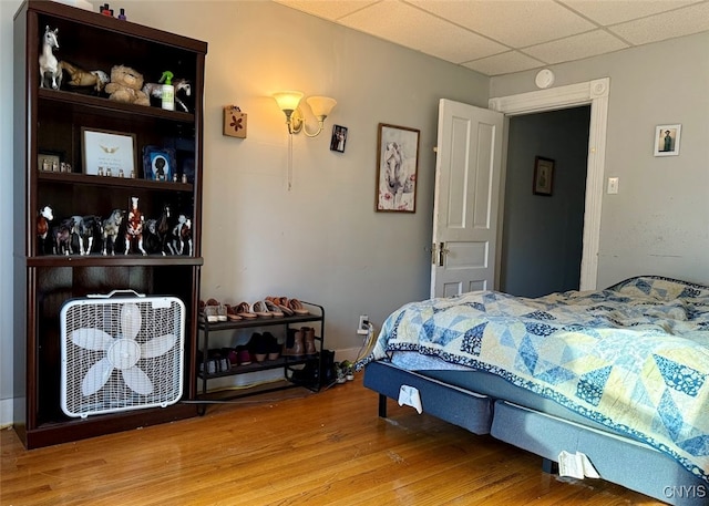 bedroom with a paneled ceiling and wood-type flooring