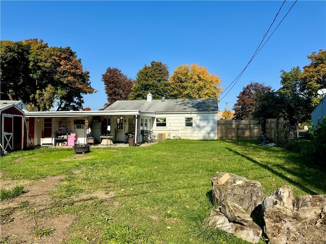 back of property featuring a patio area, a fire pit, and a lawn