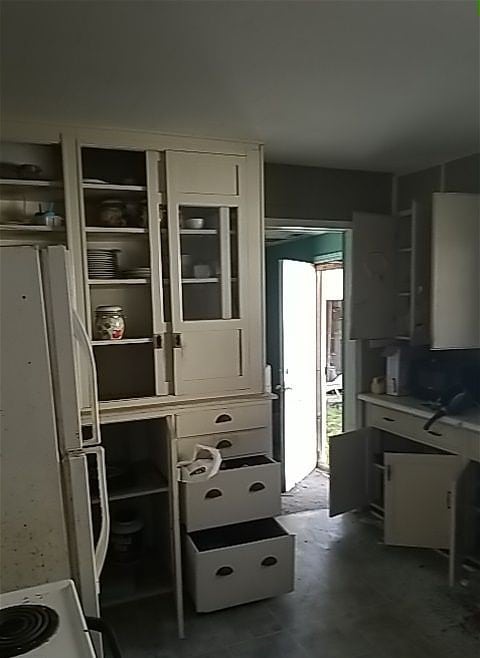 kitchen with stove, concrete flooring, and white refrigerator