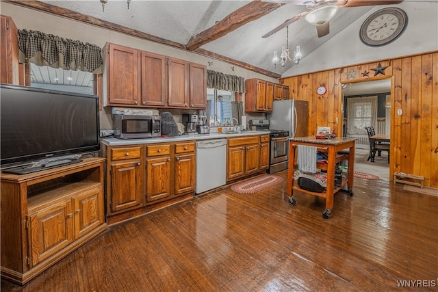 kitchen with appliances with stainless steel finishes, wood walls, dark hardwood / wood-style floors, and vaulted ceiling with beams