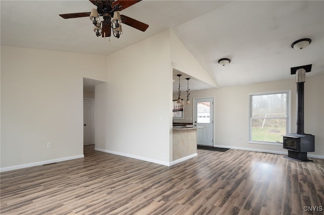 unfurnished living room with ceiling fan, wood-type flooring, lofted ceiling, and a wood stove