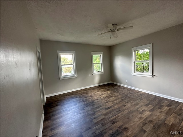 unfurnished room featuring dark wood-type flooring, ceiling fan, a healthy amount of sunlight, and a textured ceiling