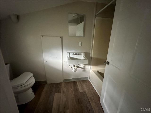 bathroom featuring toilet, shower / bathing tub combination, hardwood / wood-style flooring, and lofted ceiling