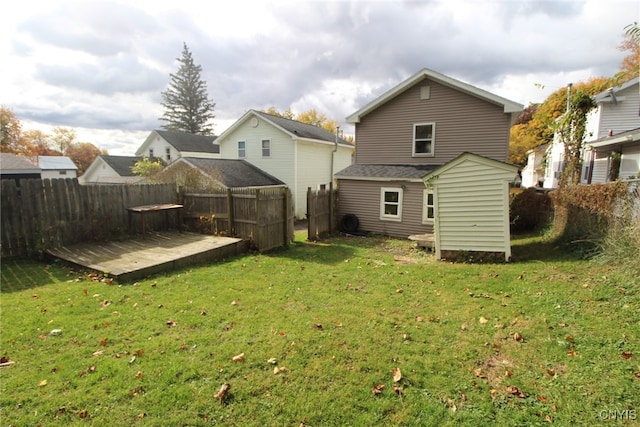 rear view of house with a wooden deck, a shed, and a lawn