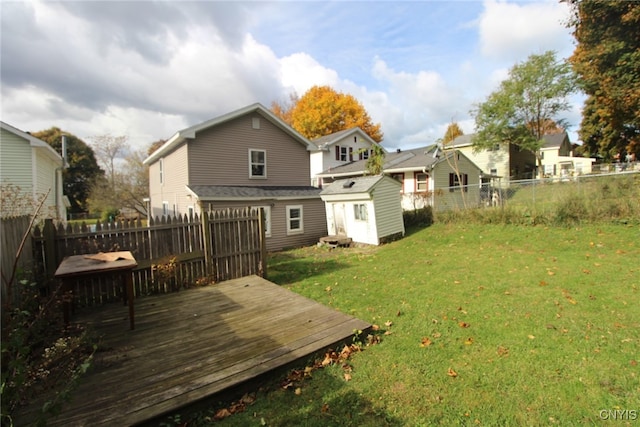 rear view of house featuring a wooden deck, a storage shed, and a lawn