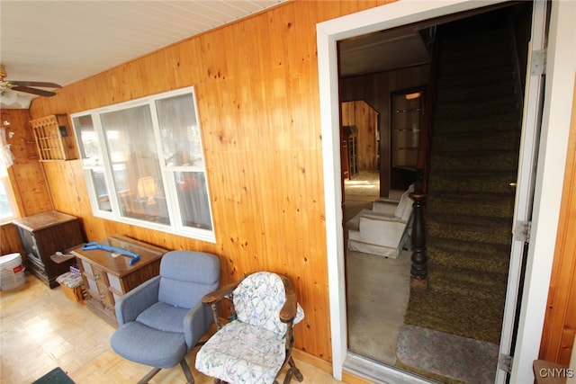 living area with light parquet flooring, ceiling fan, and wood walls