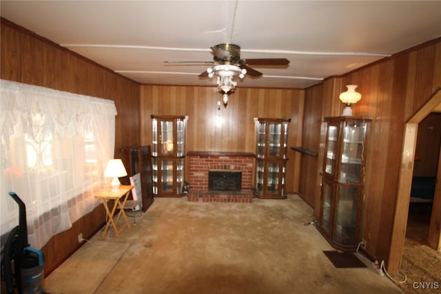 carpeted living room featuring ceiling fan, wood walls, and a brick fireplace