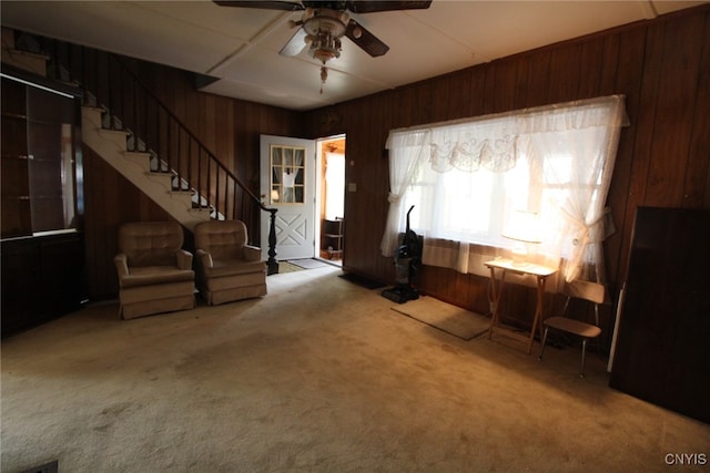 unfurnished living room featuring ceiling fan, wood walls, and carpet flooring