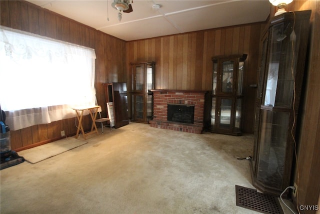 carpeted living room with wooden walls and a brick fireplace