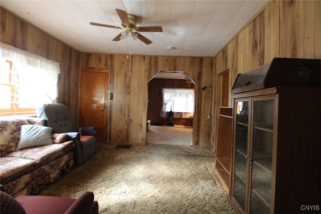 living room with wooden walls, carpet floors, and ceiling fan