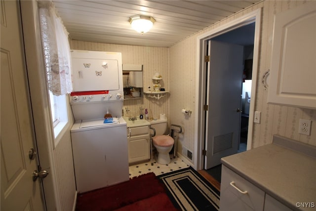 bathroom featuring toilet, stacked washing maching and dryer, and wooden ceiling