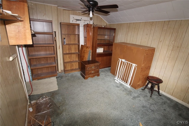 interior space with wood walls, lofted ceiling, carpet flooring, and ceiling fan