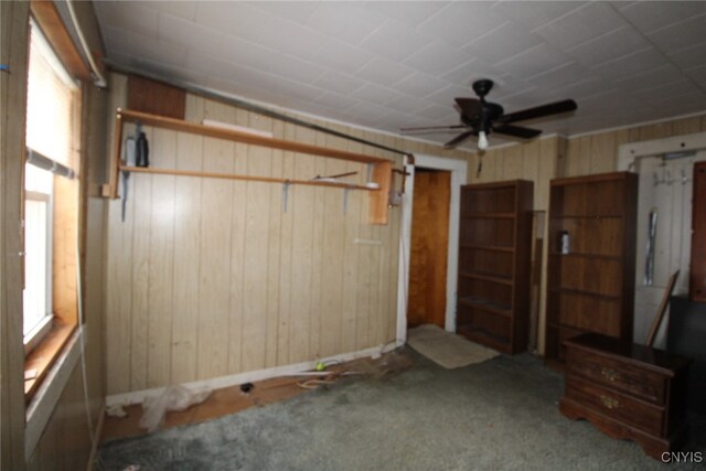 unfurnished bedroom with wood walls, carpet flooring, and ceiling fan