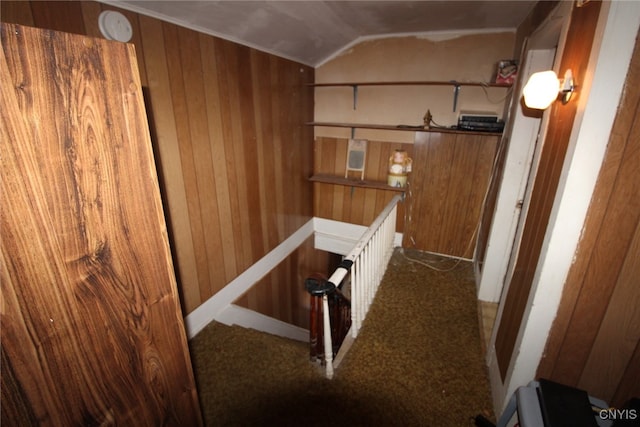 staircase with wood walls, carpet, and lofted ceiling