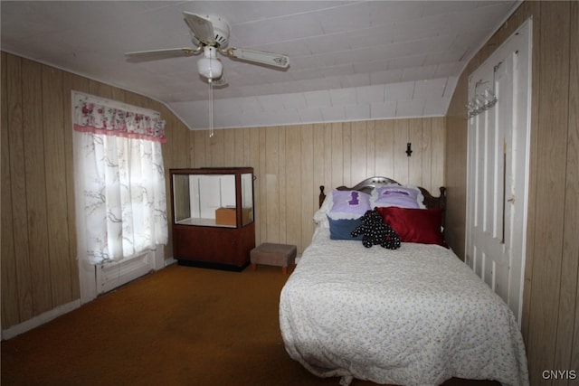 bedroom with ceiling fan, wood walls, carpet flooring, and vaulted ceiling