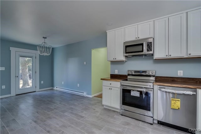 kitchen featuring pendant lighting, appliances with stainless steel finishes, a baseboard radiator, butcher block countertops, and a chandelier