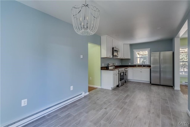 kitchen featuring appliances with stainless steel finishes, light wood-type flooring, a baseboard radiator, and pendant lighting