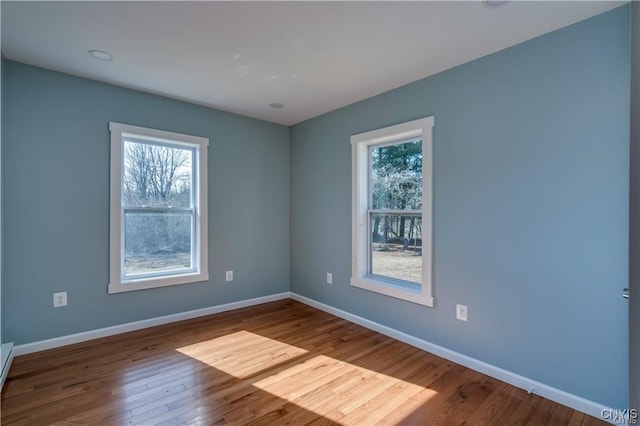 spare room featuring wood-type flooring and a healthy amount of sunlight