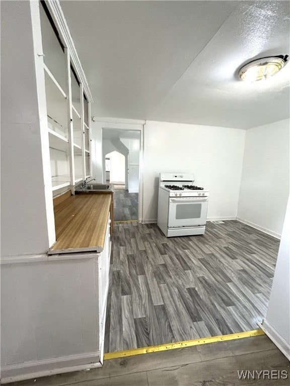 kitchen featuring dark wood-type flooring, white gas range oven, and sink