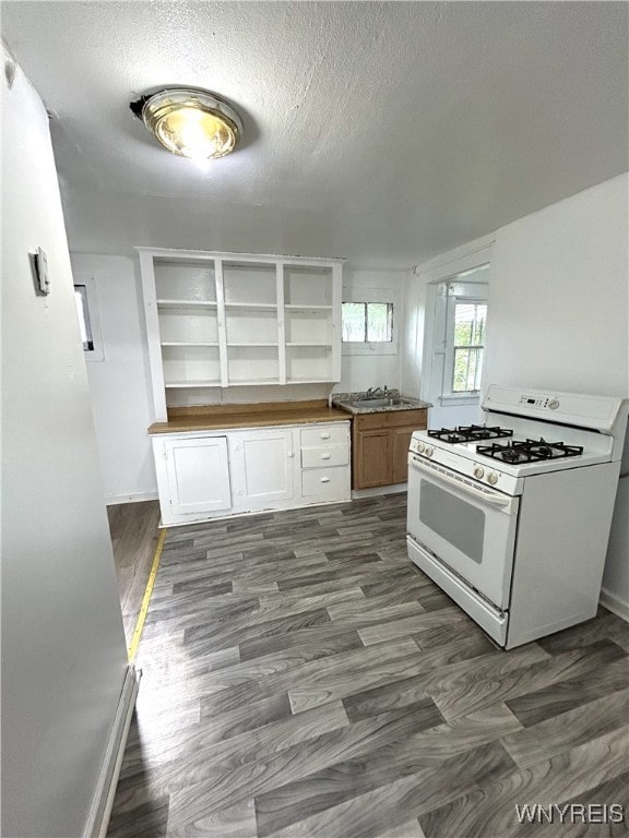 kitchen with white cabinetry, a textured ceiling, dark hardwood / wood-style flooring, and gas range gas stove