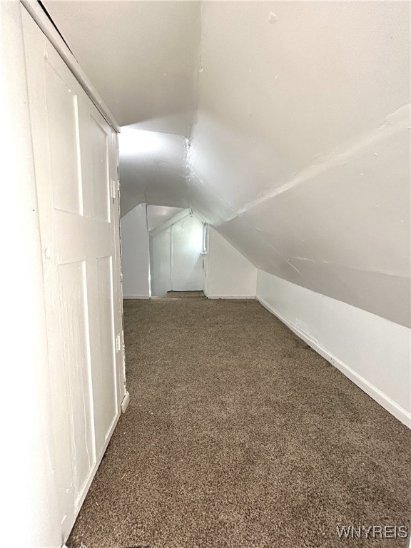 additional living space featuring lofted ceiling and dark colored carpet