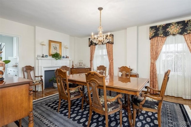 dining room with wood finished floors, a notable chandelier, and a fireplace