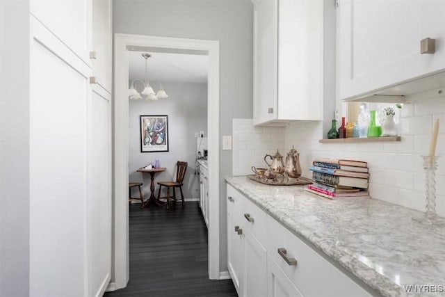 interior space featuring tasteful backsplash, dark wood finished floors, white cabinetry, and a chandelier