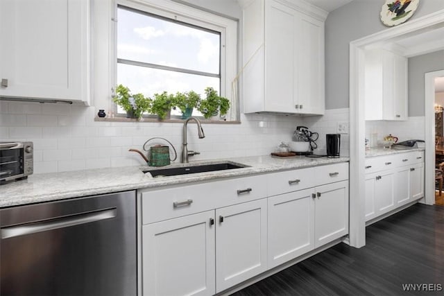 kitchen featuring white cabinets, light stone counters, a sink, dishwasher, and tasteful backsplash