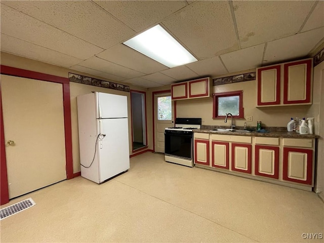 kitchen featuring gas stove, white fridge, sink, and a drop ceiling