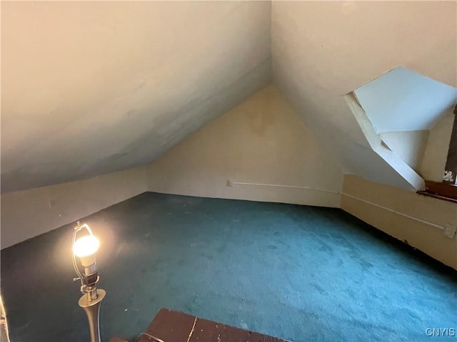 additional living space featuring lofted ceiling and dark carpet